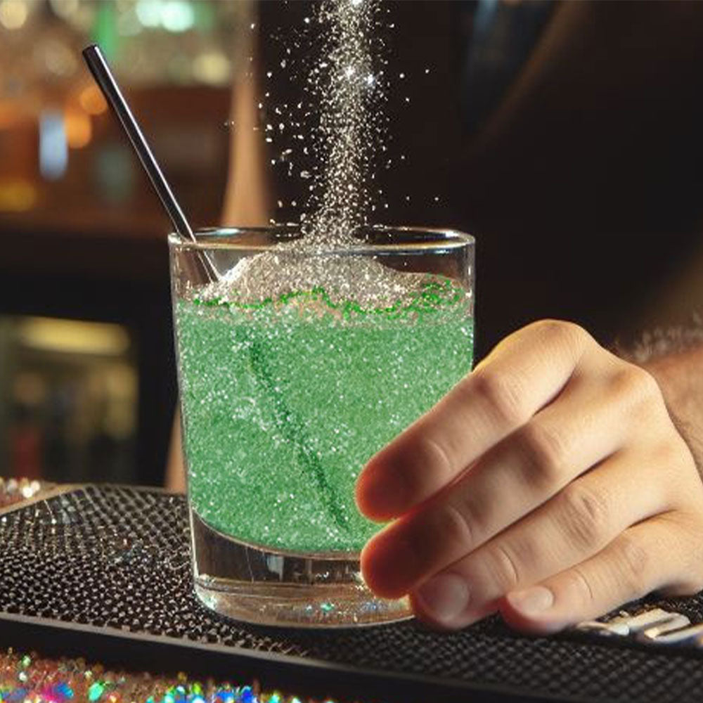 sprinkling green glitter onto a cocktail in a rocks glass